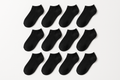 12 pairs of plain black low cut socks on white background